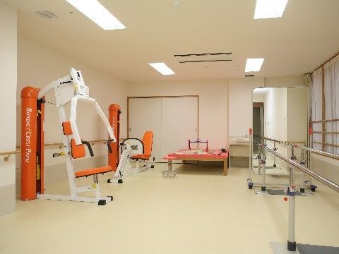 白を基調とした開放的な機能訓練室。平行棒やレッグプレスなどの種類の違うトレーニング器具が複数置かれている。