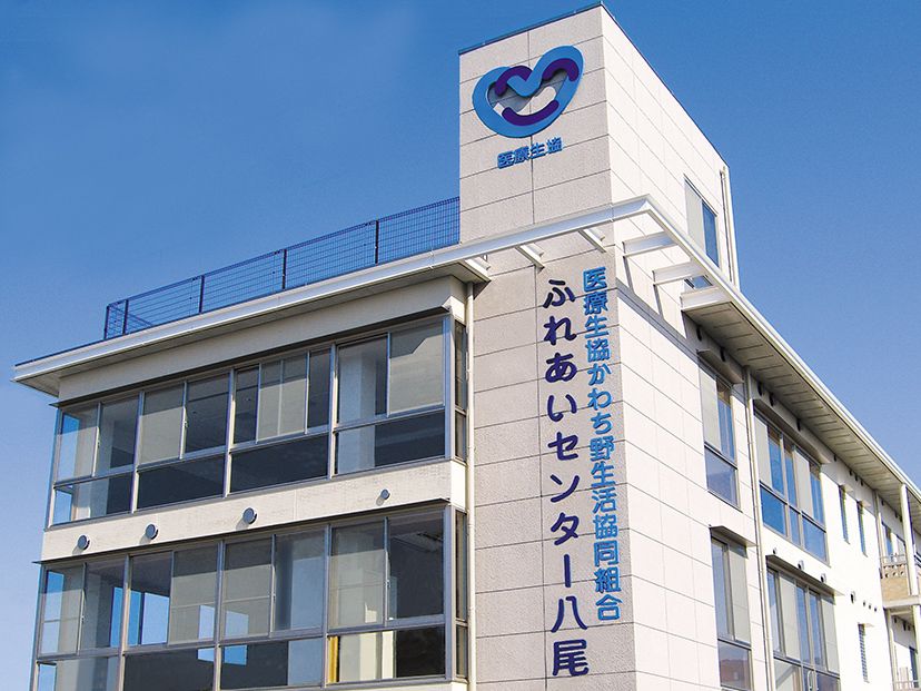 白を基調とした3階建ての建物にブルーのラインが入った建物。外壁に青で施設の名前が書かれている。