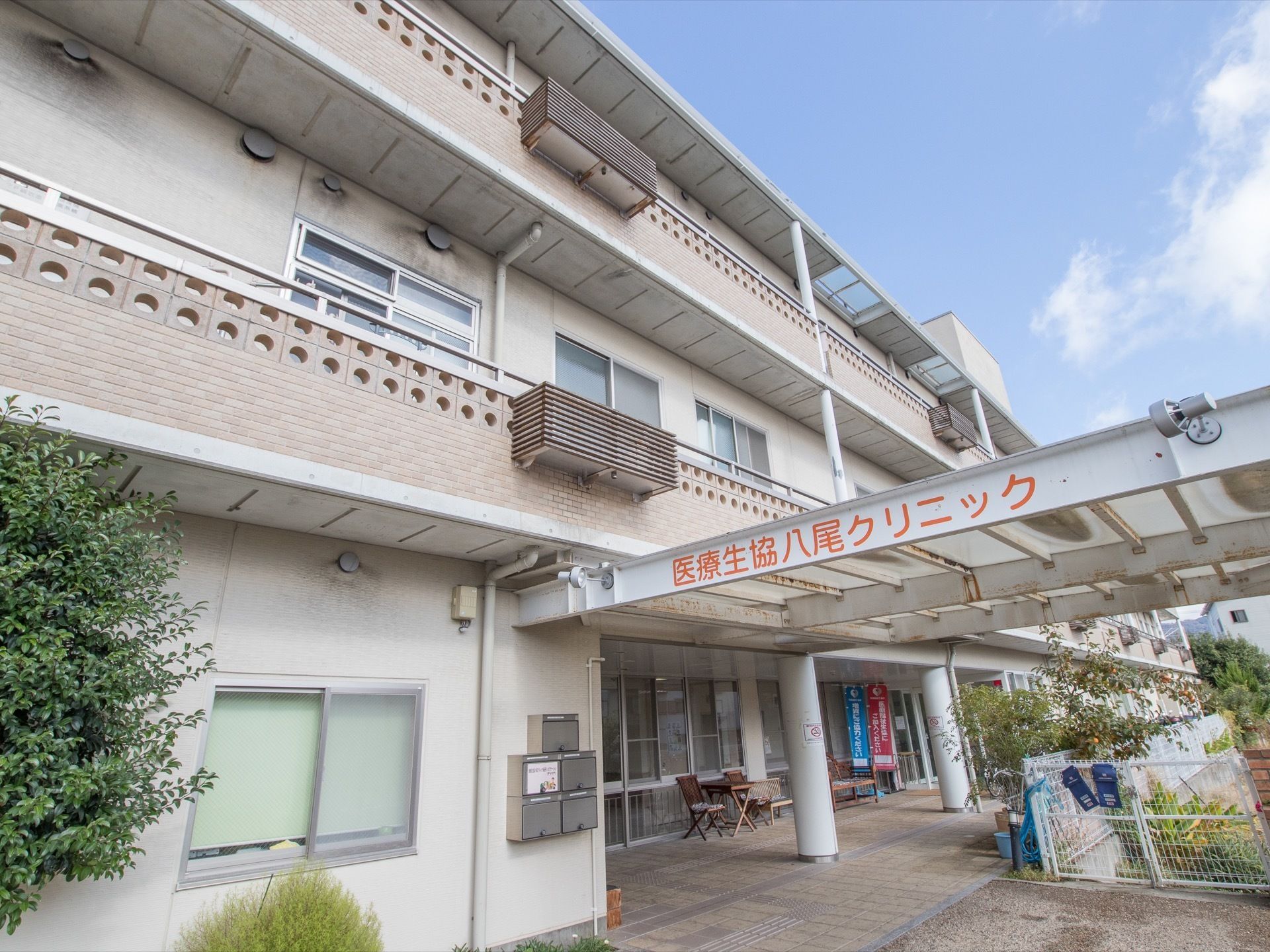 建物の外壁は、グレーでまとめられている。玄関ポーチの金属製の梁の部分に、医療機関の名称が表示されている。