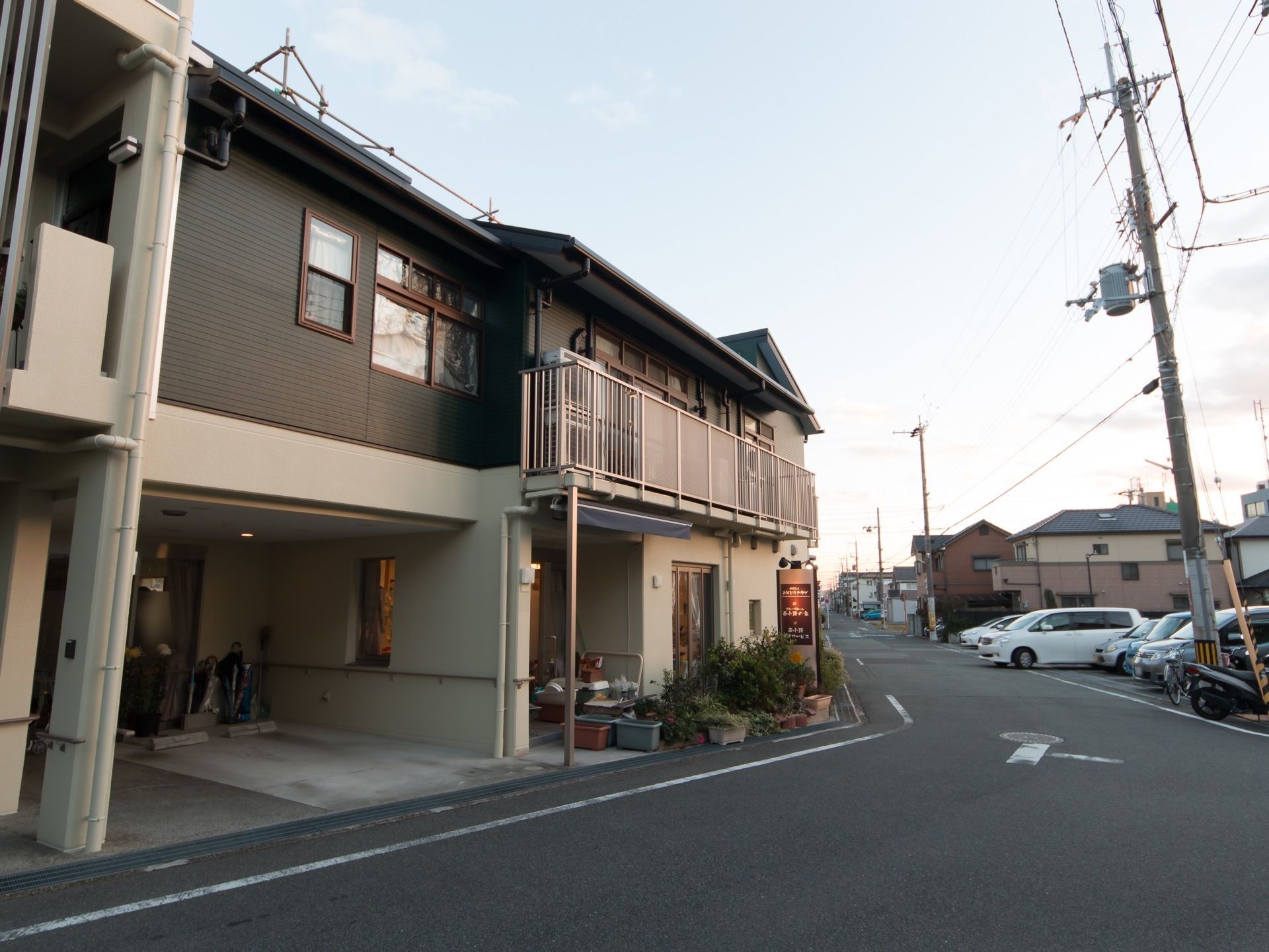 住宅地に立地している2階建て施設の外観である。一般住宅のような設えで、施設看板が立てかけられている。