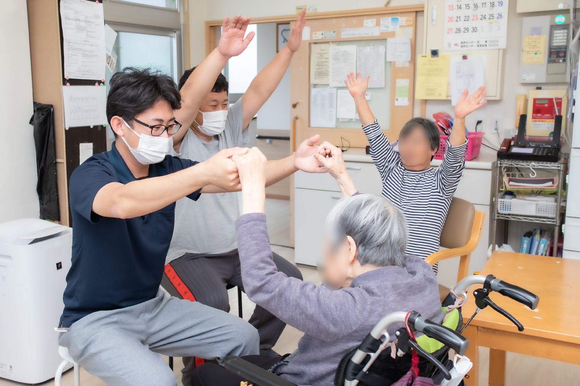 服薬をうながすスタッフとそれに従って薬を飲もうとしている女性。施設内の一場面
