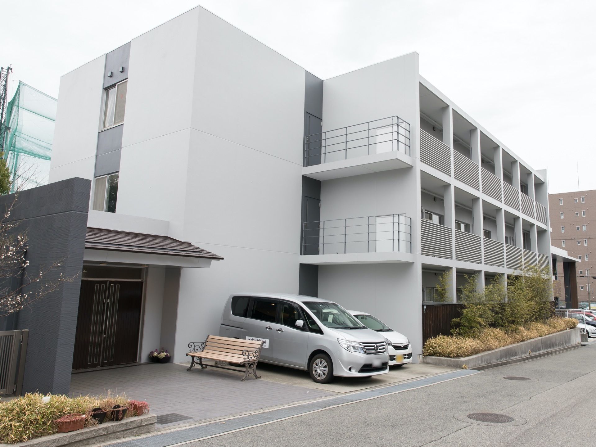 白を基調とした３階建ての住まいで、建物前には花壇が設けられている。館内までのアプローチは段差がない。