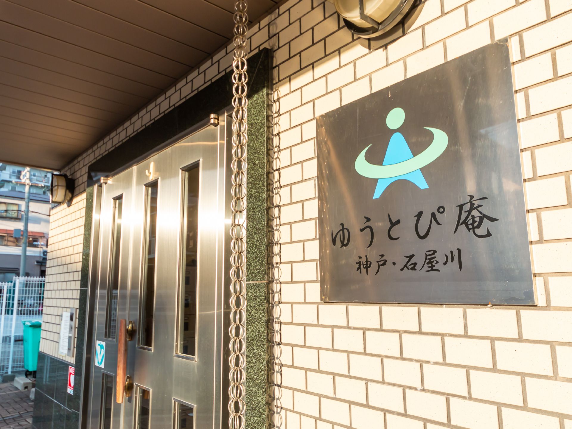 高齢者の方にタオルをかけてマッサージしているスタッフと振り返りながら会話する女性の様子