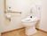 トイレは水洗トイレ。壁には手すりとトイレのスイッチが設置されている。呼び出しスイッチには紐があるので簡単に呼び出せる。