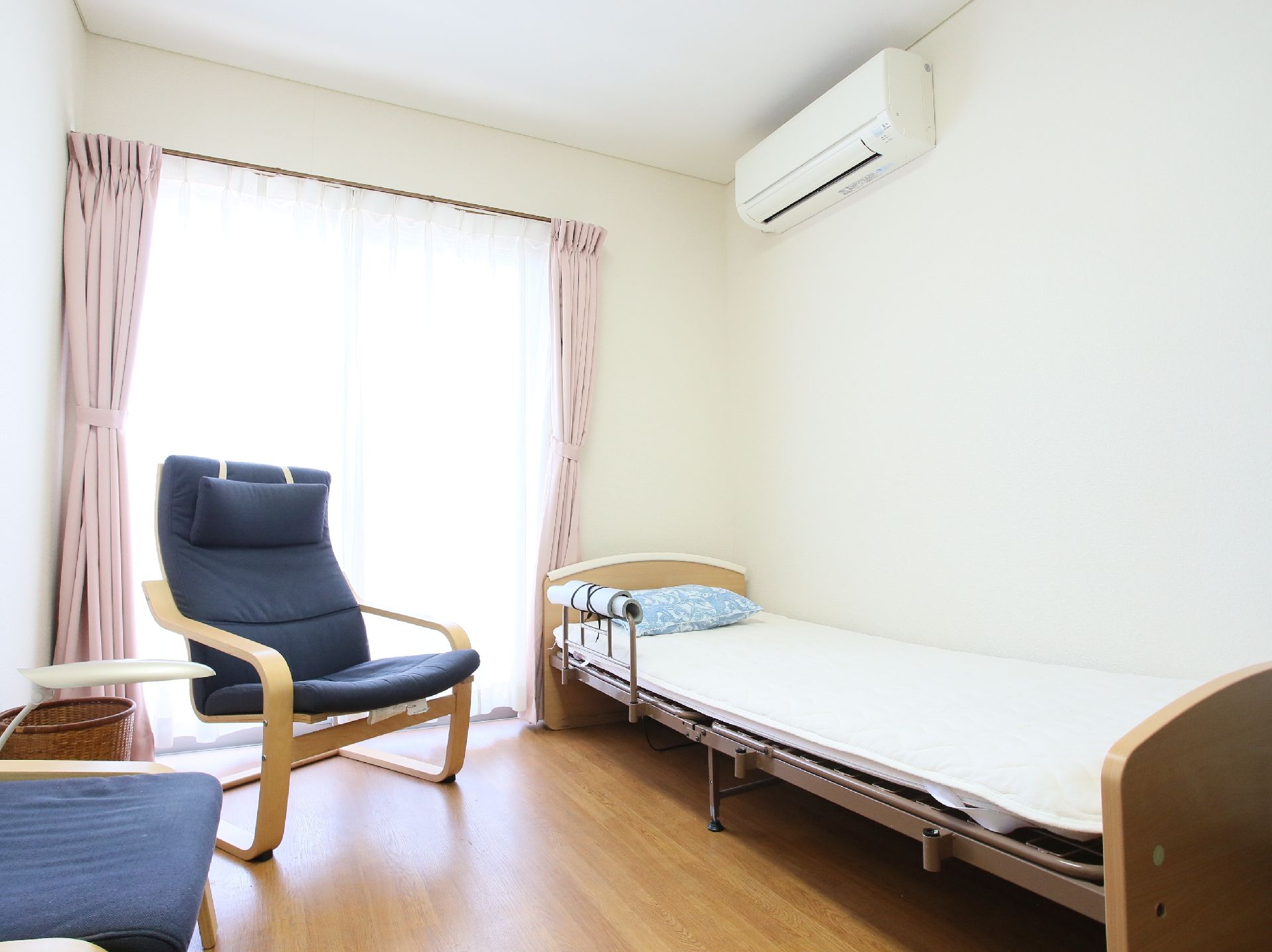 柵付きのベッドと椅子が置かれている、大きな窓のある部屋
