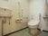 淡いピンク色の手洗い場、温水洗浄便座が備えつけられたトイレである。Ｌ字型の手すりを完備している。ナースコールもある。