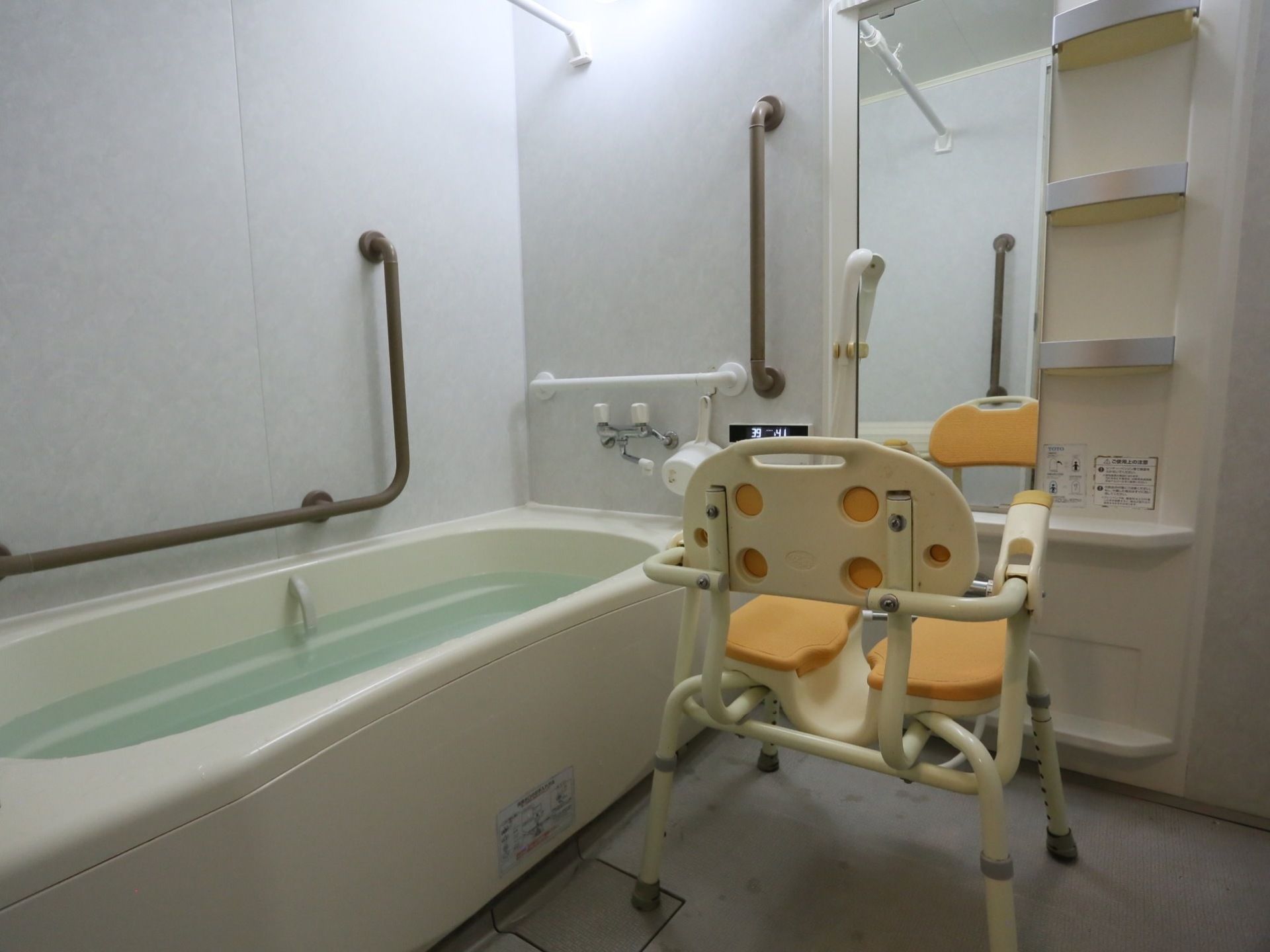清潔感のある浴室には介助用の椅子がある。金属製でしっかりとした造りになっており、入居者様は安心して座ることができる。