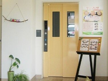 エレベーターが設置された館内。エレベーターの両サイドには写真や観葉植物、写真などが飾られている。