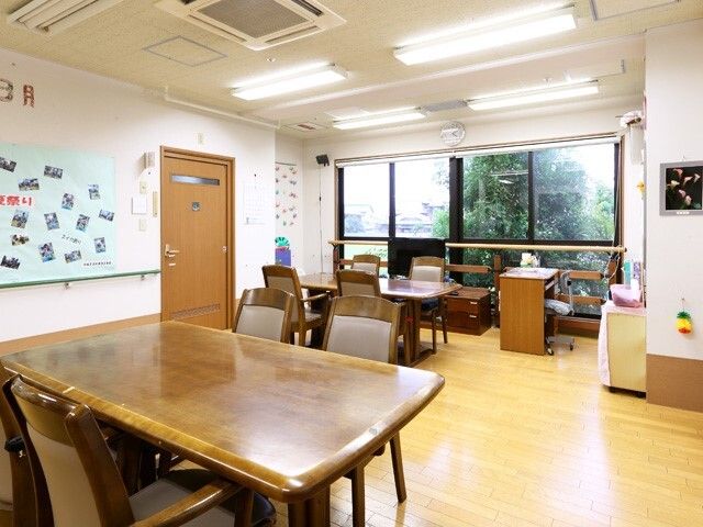 木製のダイニングテーブルセットが複数置かれた食堂の壁には写真が貼られ、テレビも設置されている。