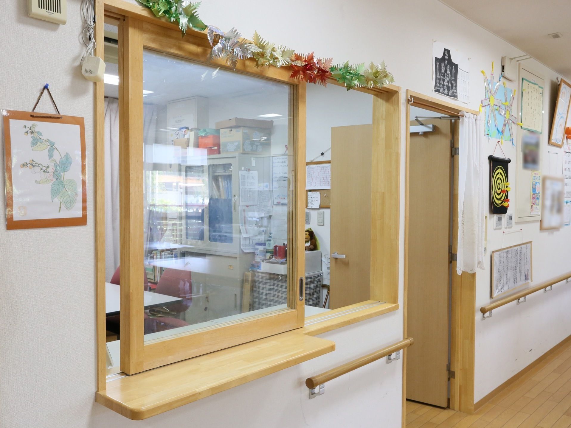 大きな窓の開放的な受付である。壁面は、入居者様やスタッフ手作りの作品が飾られており、親しみやすい雰囲気である。