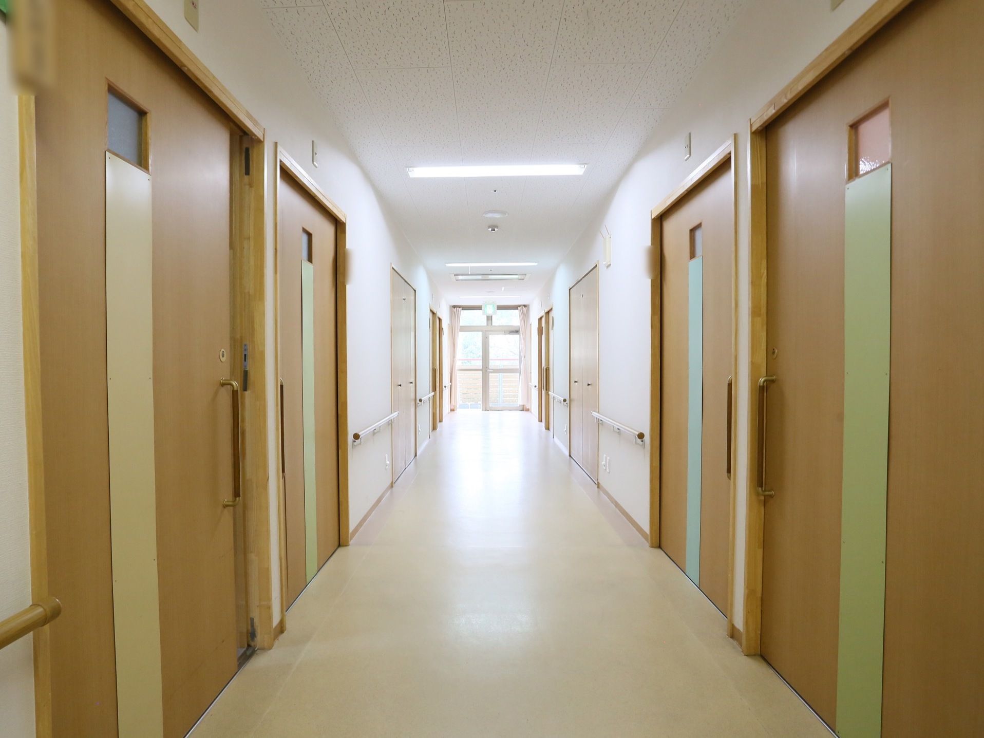 広くて手すりも設置されているので、通行がしやすい通路。白い壁と木のドアがおしゃれな印象を与えてくれる。