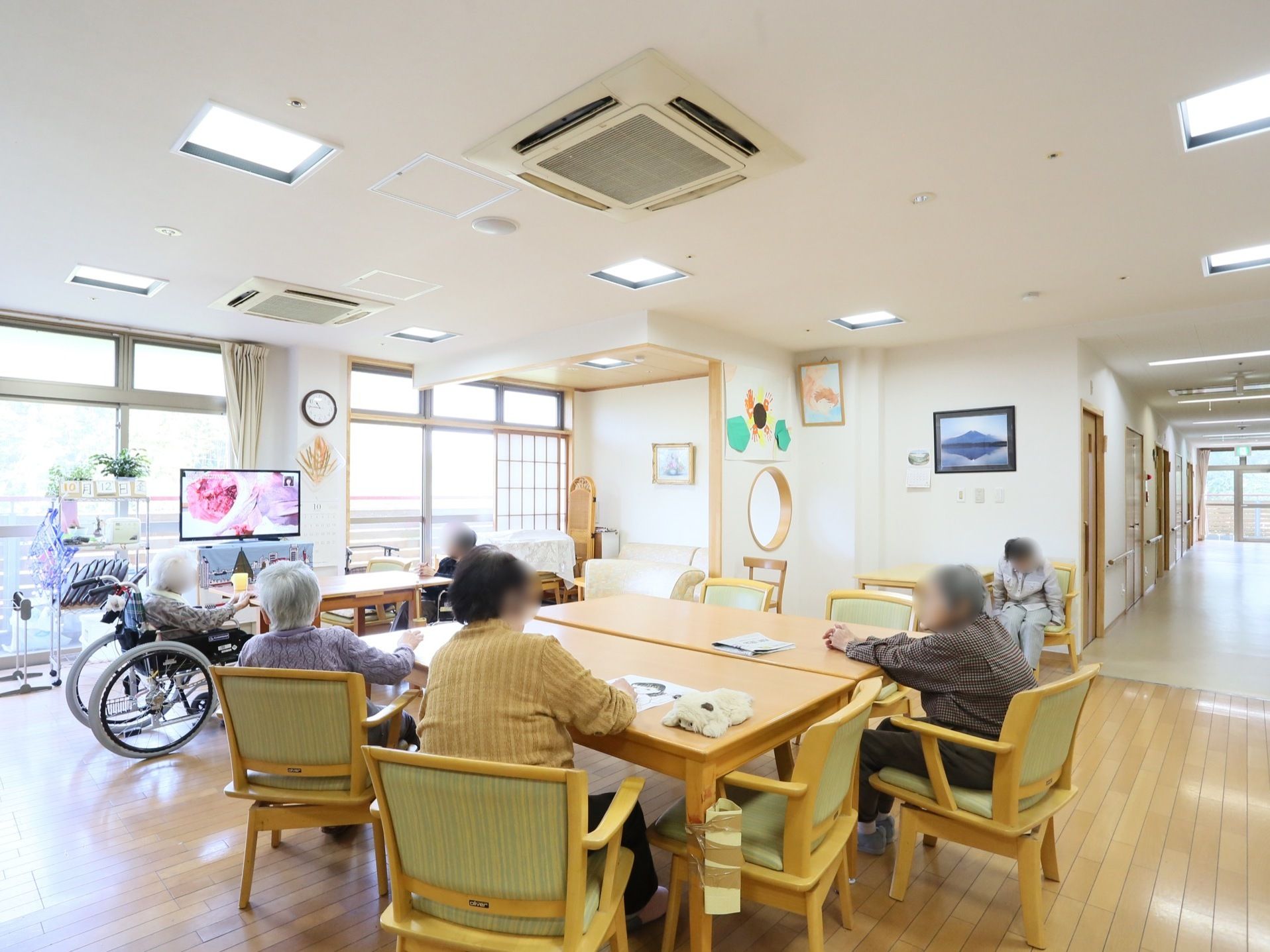 大きな窓から陽光が差し込み、白い壁とフローリングの床の明るく落ち着いた雰囲気の、共有スペースである。