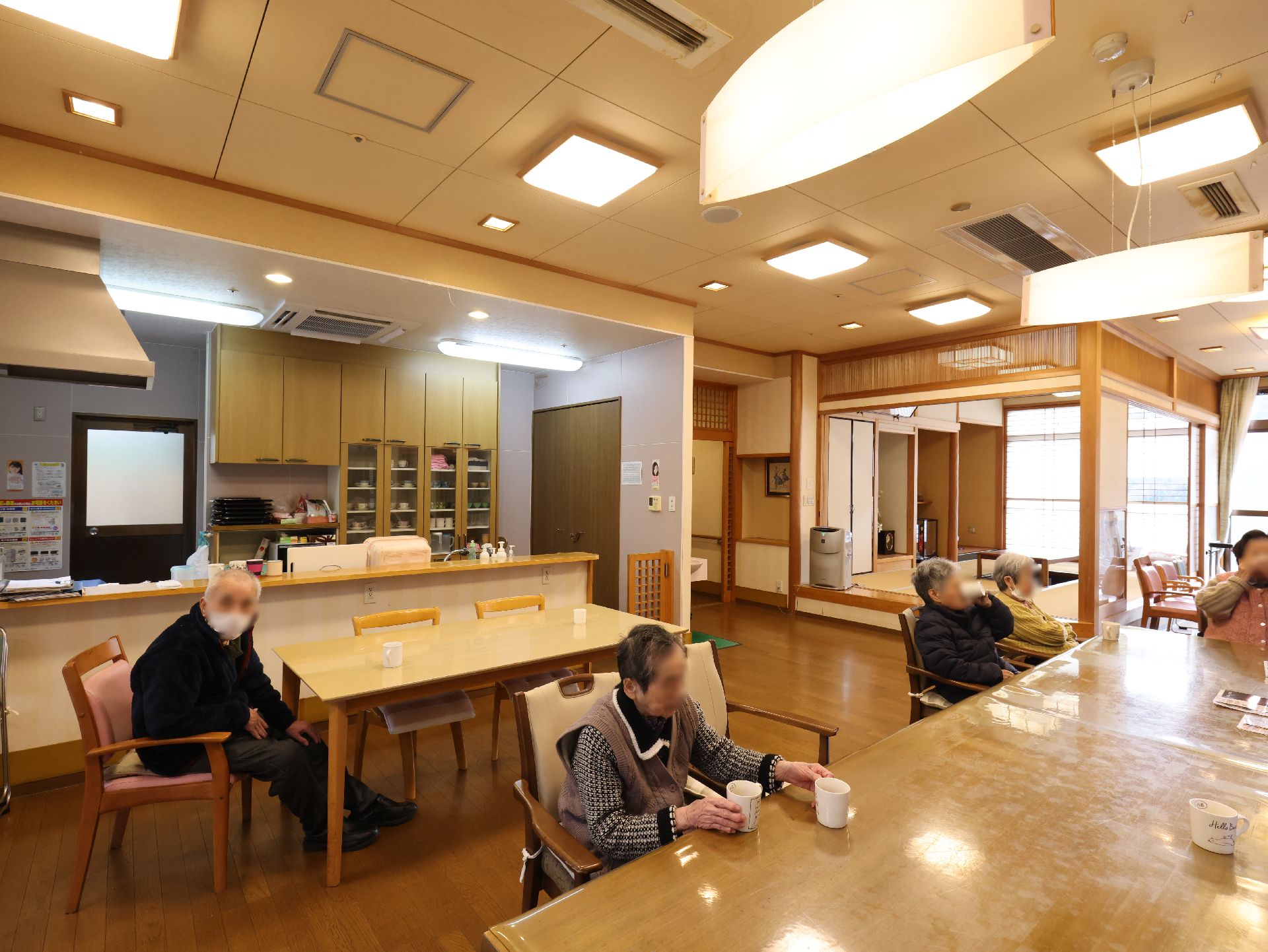 高齢者の方にタオルをかけてマッサージしているスタッフと振り返りながら会話する女性の様子