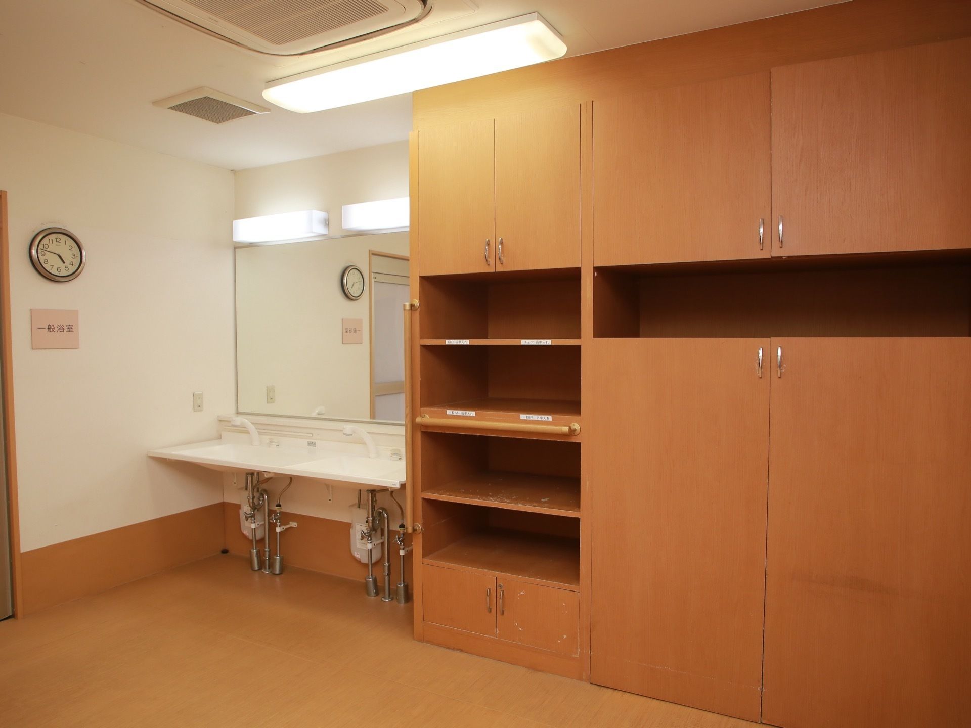 手すりのついた大きな木製の収納棚が据えられている。２つ並んだ洗面台の上には大きな鏡が設置されている。