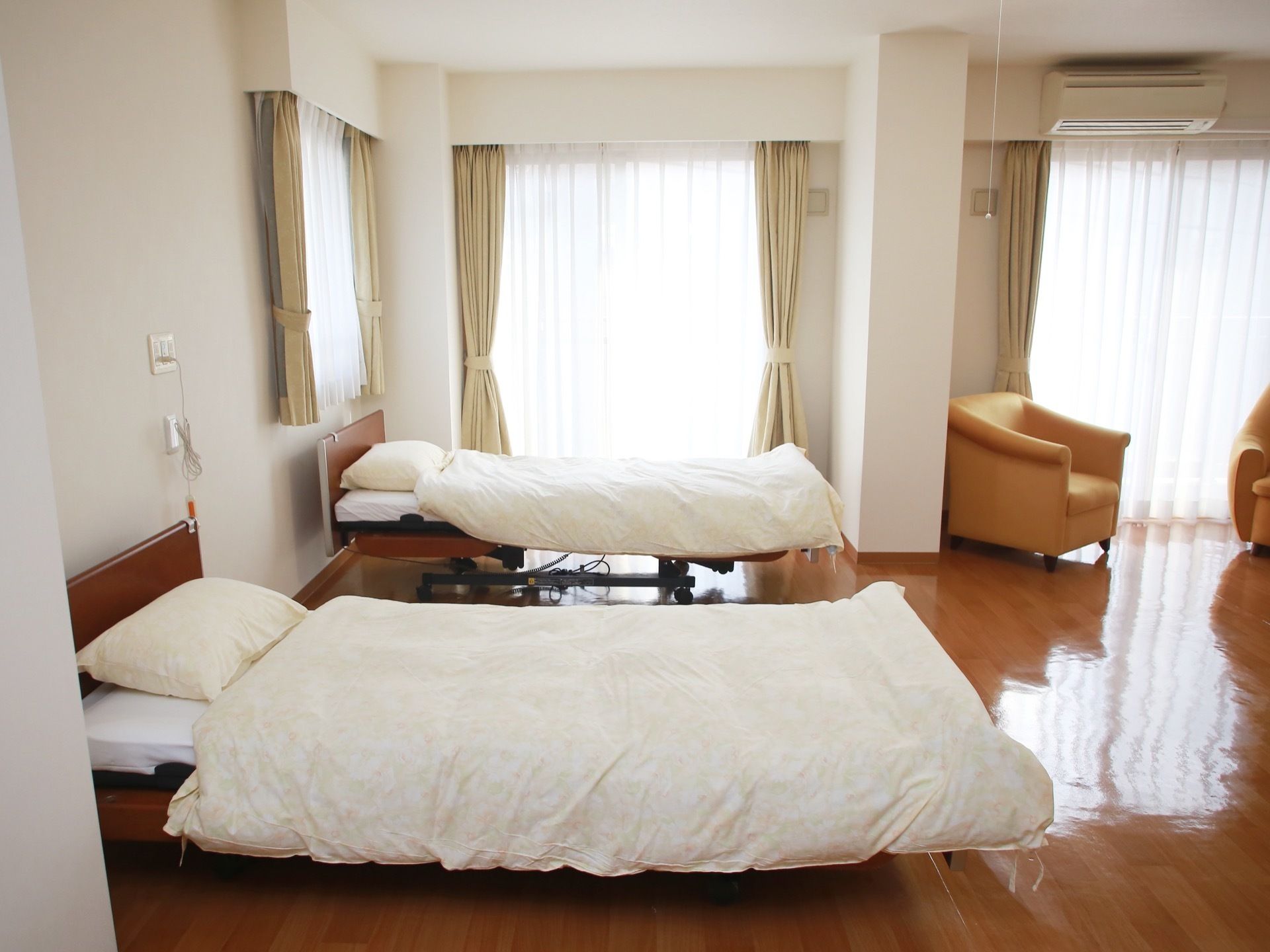 広々としたフローリングの部屋に、電動ベッド２台、一人掛けのソファ２脚が置かれている。窓が多く、陽光が差し込んでいて明るい。