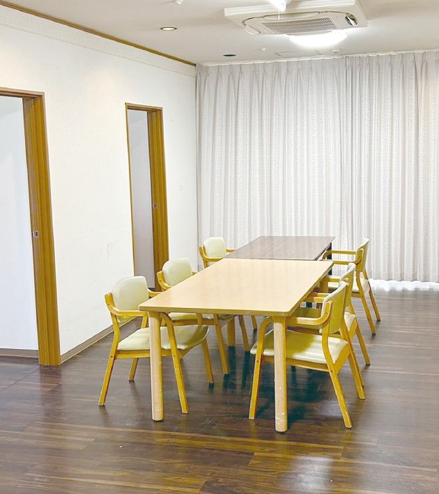 笑顔で話をしている女性スタッフと高齢夫婦。芝生の上に並んで座っている。
