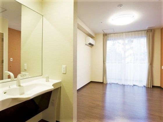 洗面所とエアコン付きのフローリングの居室にはカーテンが設置された大きな窓が付いている。