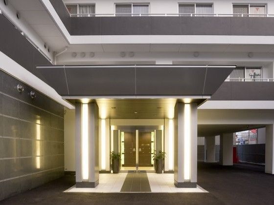 重厚感のある玄関。車寄せが付き、ドアは自動ドア。周辺は薄暗く、ライトアップされている。