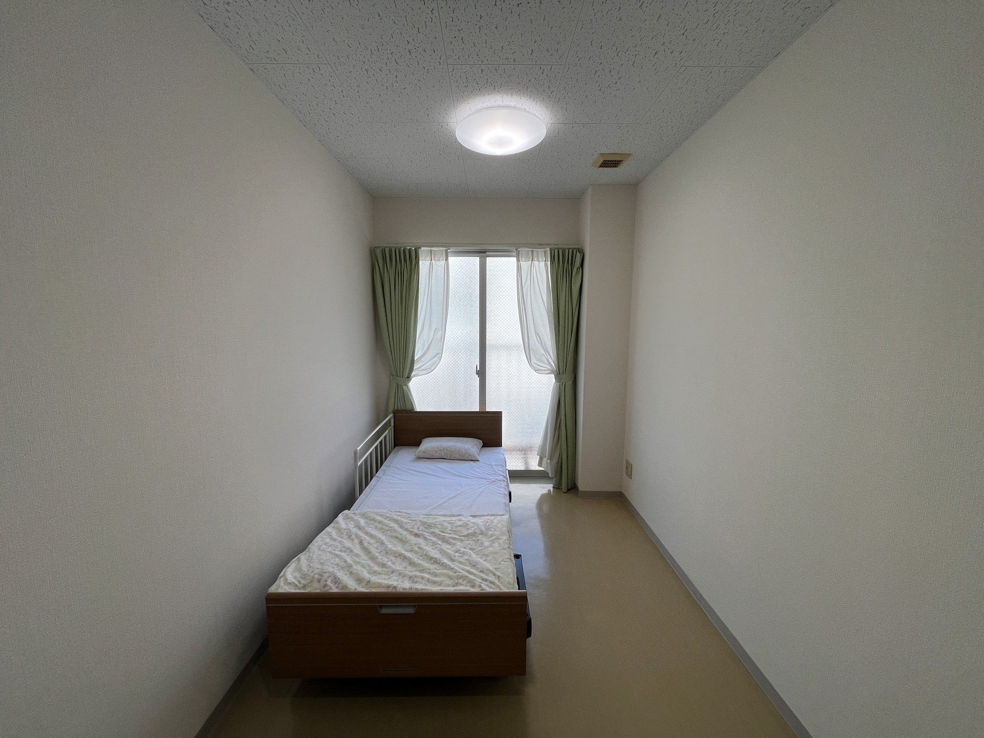 白い花がたくさん咲く道を散歩する車椅子に乗った高齢女性と介助をするヘルパー