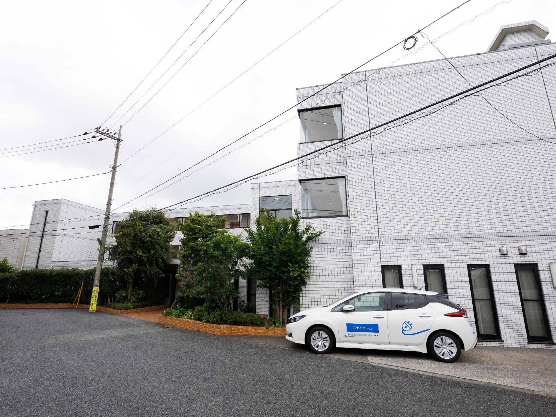 白い壁の建物の近くに止まった白い車