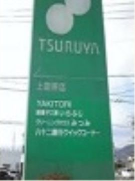 スーパーマーケットの看板の写真である。緑色を基調とした大きな四角いパネルに、白い文字で施設名やロゴが描かれている。