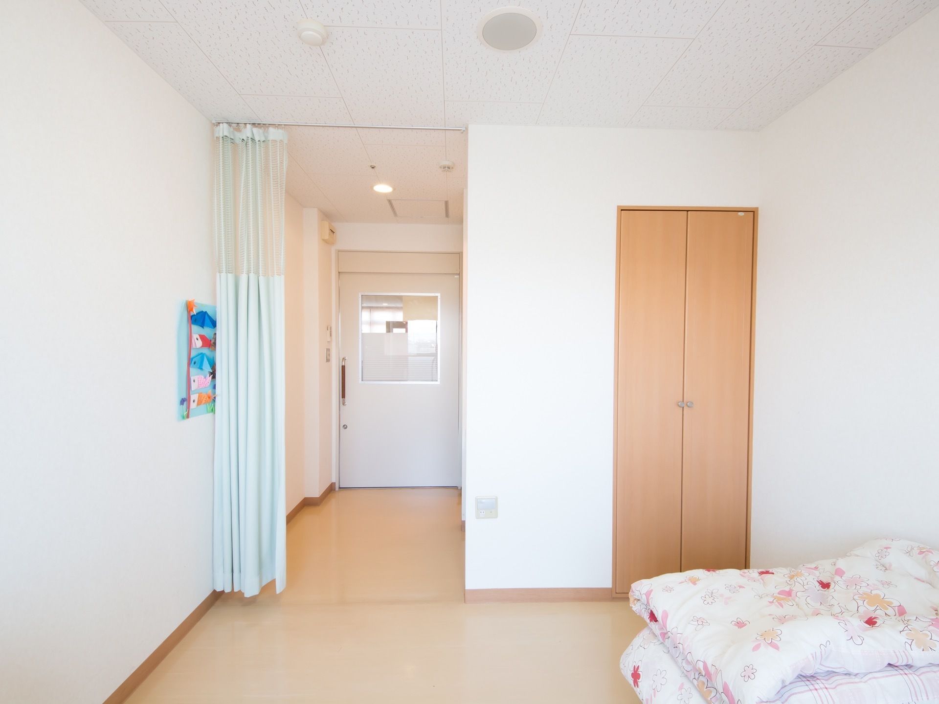 スライドドアを開けるとカーテンの仕切りがあり、部屋が丸見えにならないように工夫されている。室内は白を基調として清潔感がある。