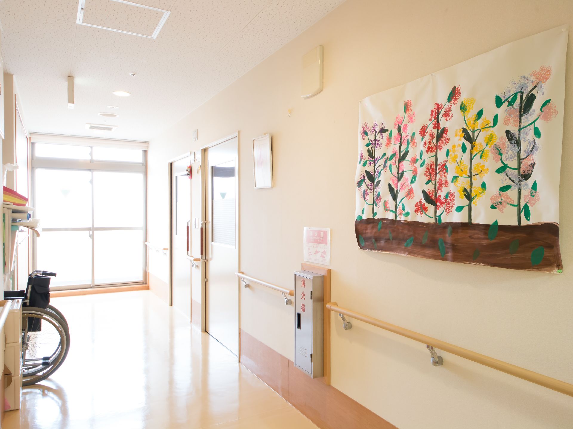 壁に花が描かれた作品が飾られている、手すりがついた広い廊下