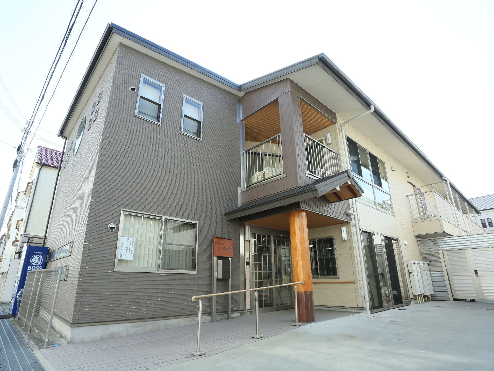 白色と灰色を基調とした外壁の２階建ての施設である。玄関前にはゆるやかなスロープがあり、手すりが設置されている。