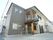白色と灰色を基調とした外壁の２階建ての施設である。玄関前にはゆるやかなスロープがあり、手すりが設置されている。