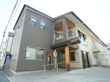 白色と灰色を基調とした外壁の２階建ての施設である。玄関前にはゆるやかなスロープがあり、手すりが設置されている。