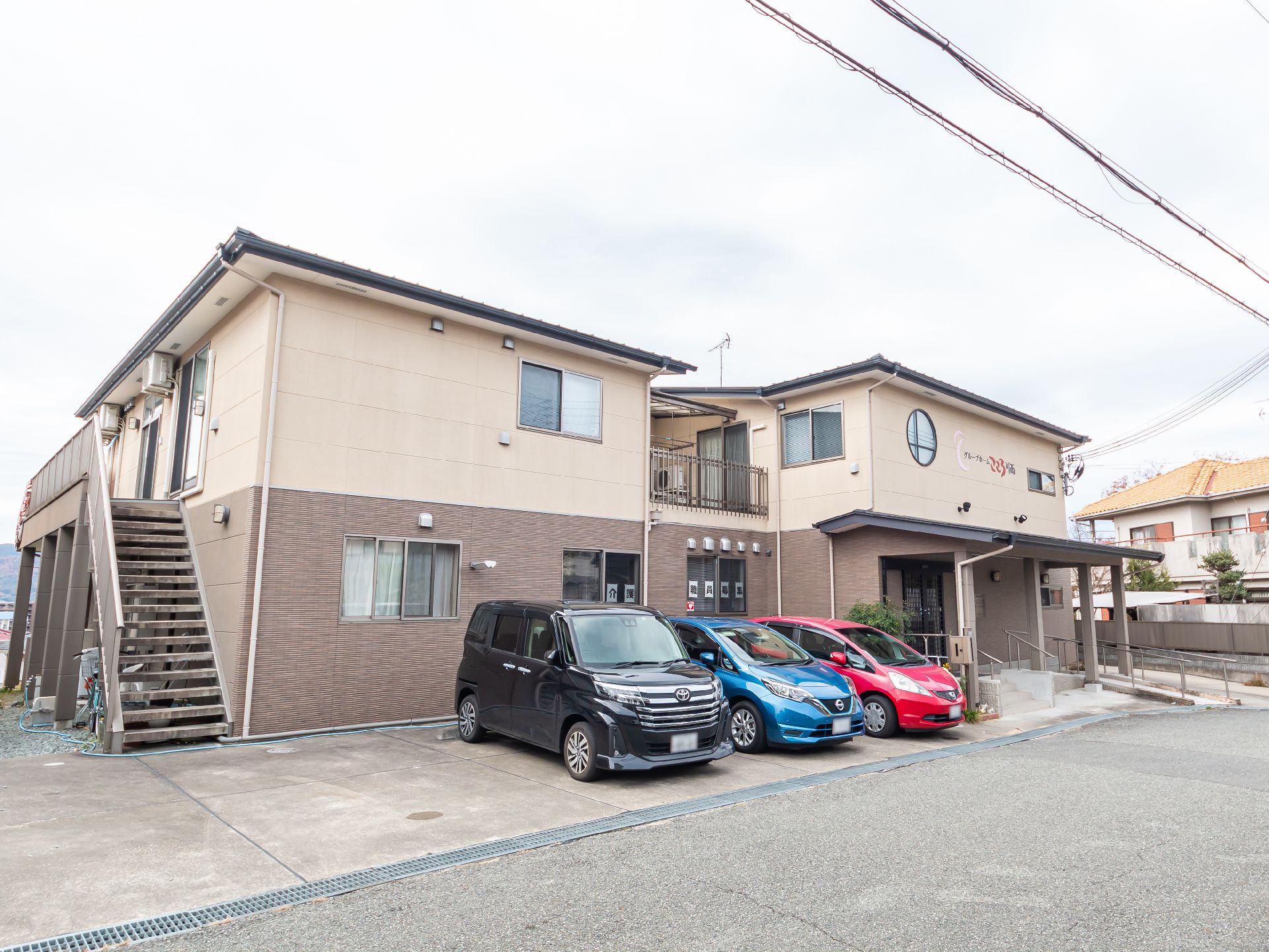 広い駐車場が隣接している、おしゃれな屋根のある介護施設