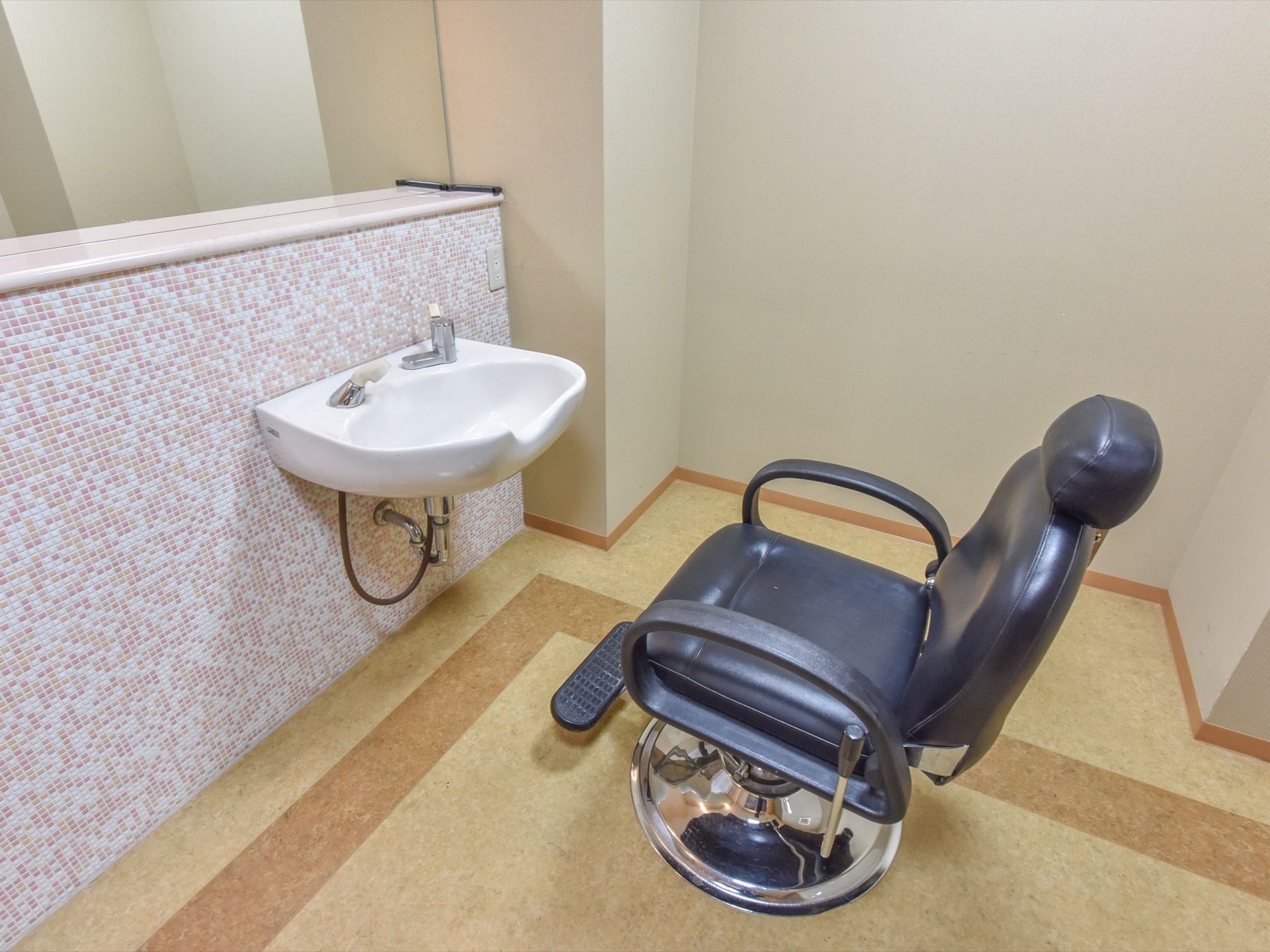 シャンプー台が設置されている壁のデザインは、白、ピンク、ベージュ色のタイルが組み合わされたカラフルな色合いになっている。