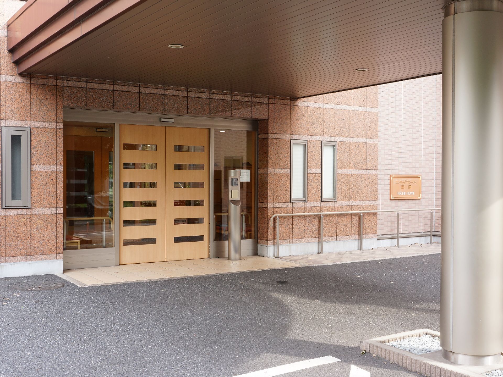 施設の玄関扉は薄い茶色で、上部には屋根が付いている為、近くまで車で移動すれば濡れずに中に入ることができる。
