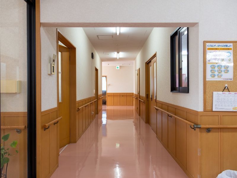 通路はピンク色の床に木目調の腰壁となっていて、両側に木製の手すりが取りつけられている。コーナー部分にコルクボードが貼られている。
