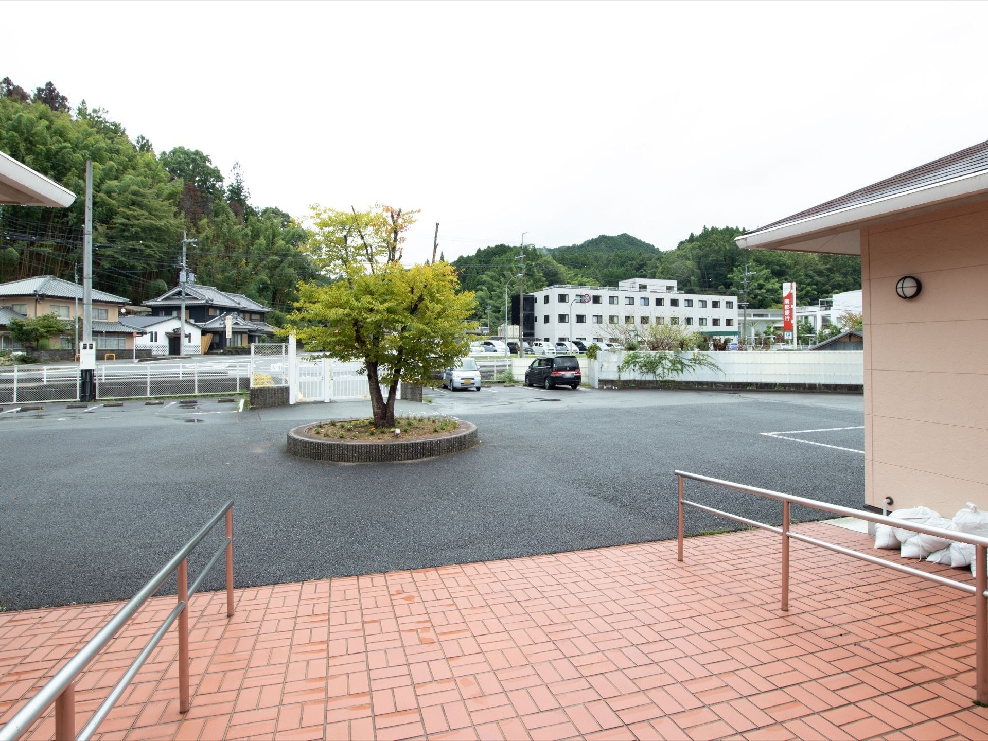 広い駐車場が完備されている。中央に木が植えらている。建物の周りには大きな建物もなく、自然が残っている。
