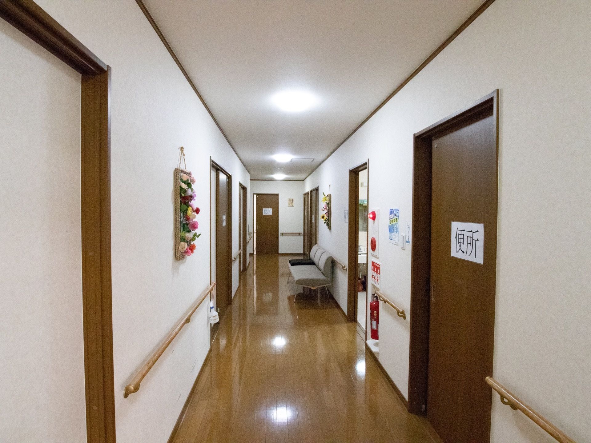 白と茶色で統一されている。手すりが随所に設置されている。消火器と非常ベルがセットで壁に据えつけてある。3人掛けのソファーが置かれている。