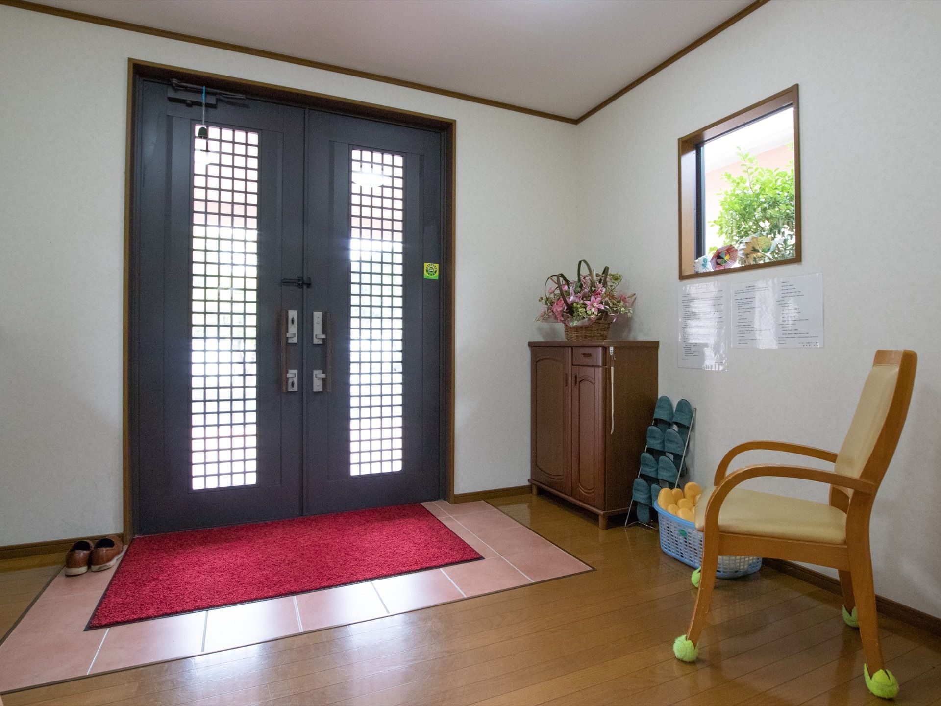 大きな開き扉になっている。段差のないフローリングで、ドアの前には玄関マットが敷かれている。椅子が用意されている。