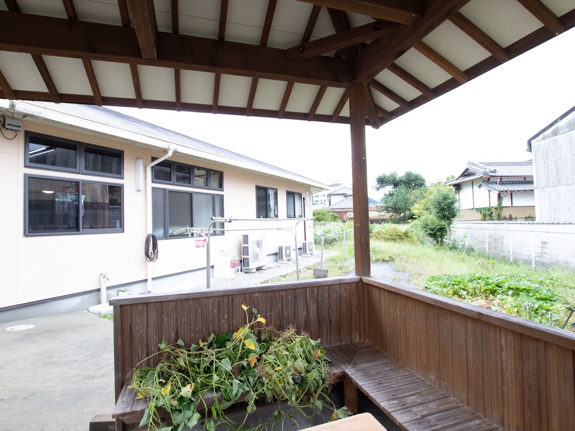 物干しが置かれている。屋根付きの休憩スペースが設置されている。畑があり、そこで収穫したものが椅子に置かれている。