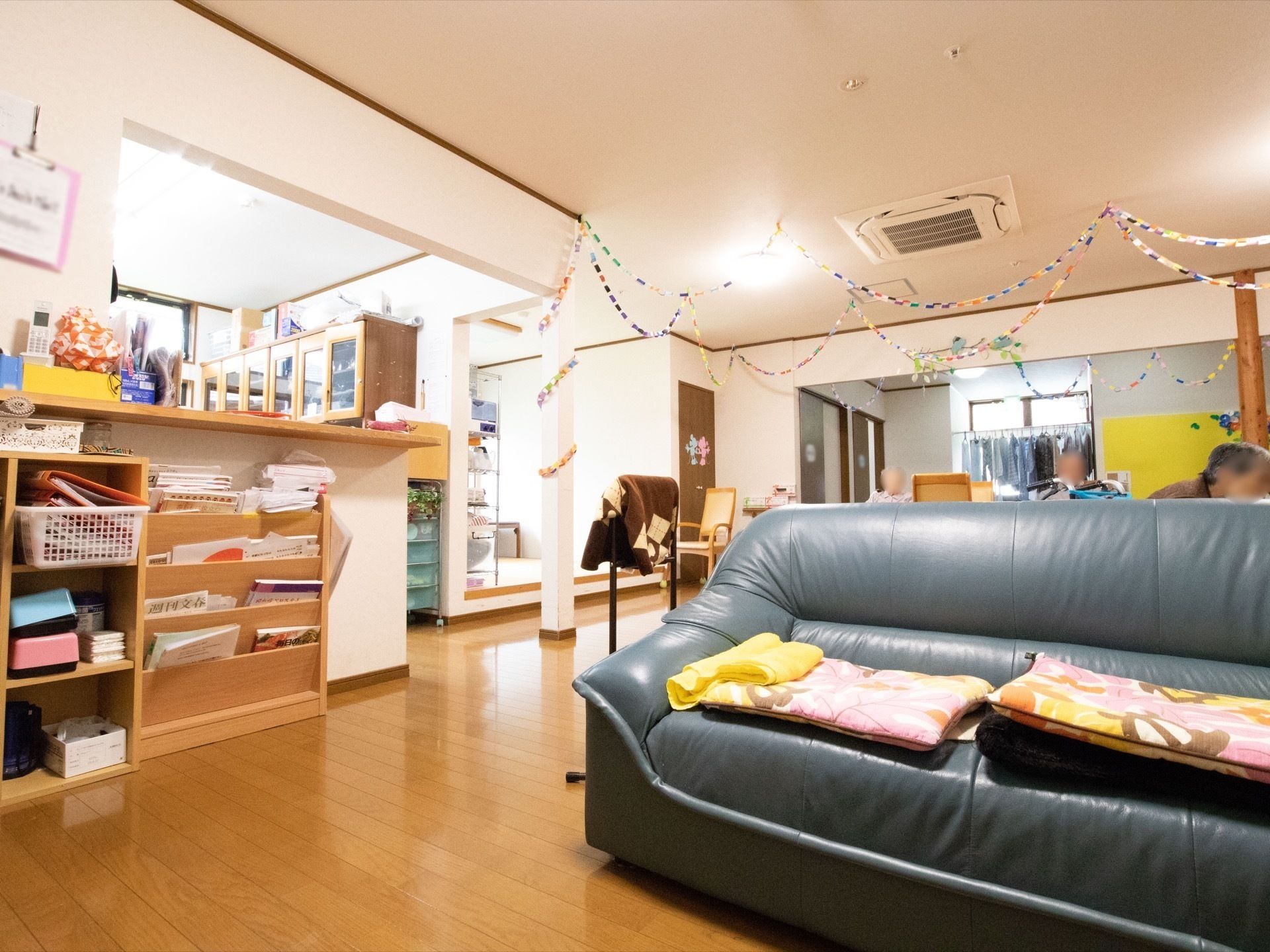 天井から紙飾りが垂れ下がっている、ソファとキッチンのある部屋