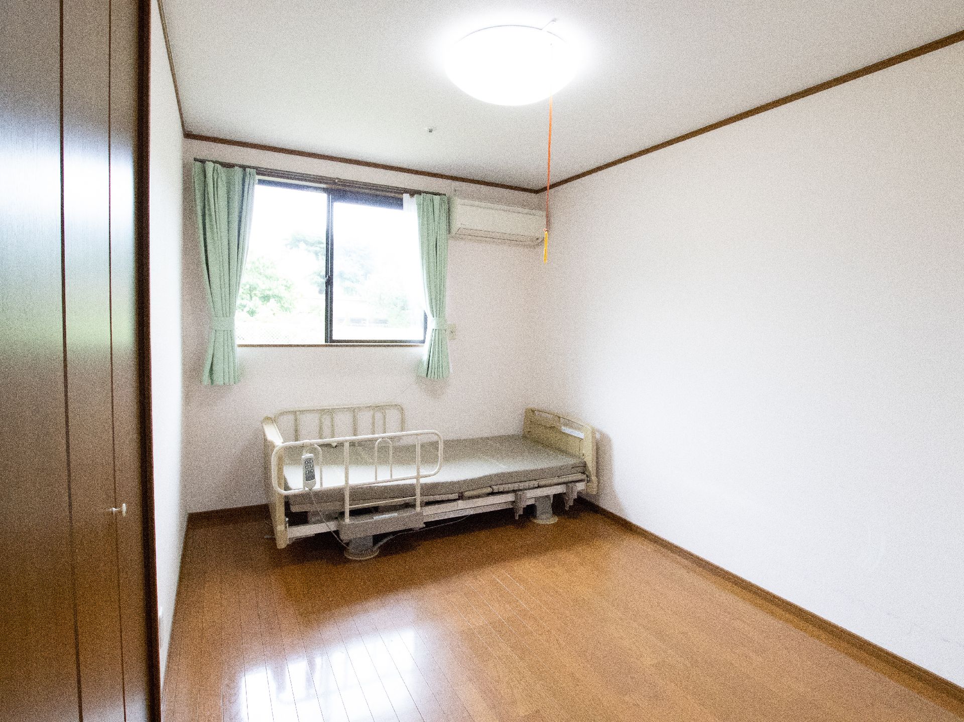 大きなクローゼットと電動ベッドがある、カーテンが開いた状態の部屋