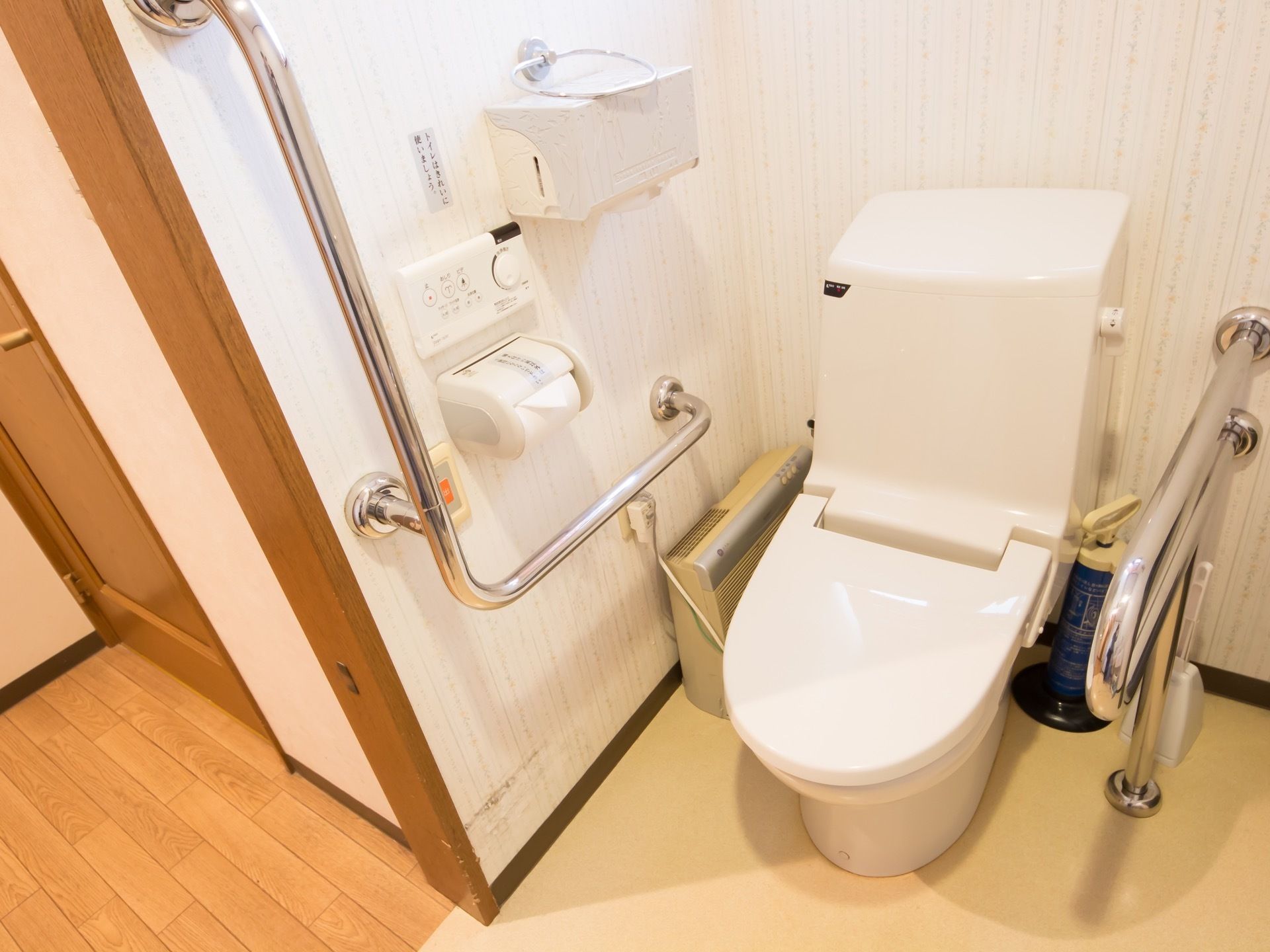 温水洗浄便座が備えられた個室トイレになっている。安全のため、手すりと緊急時のナースコールが壁に設置されている。
