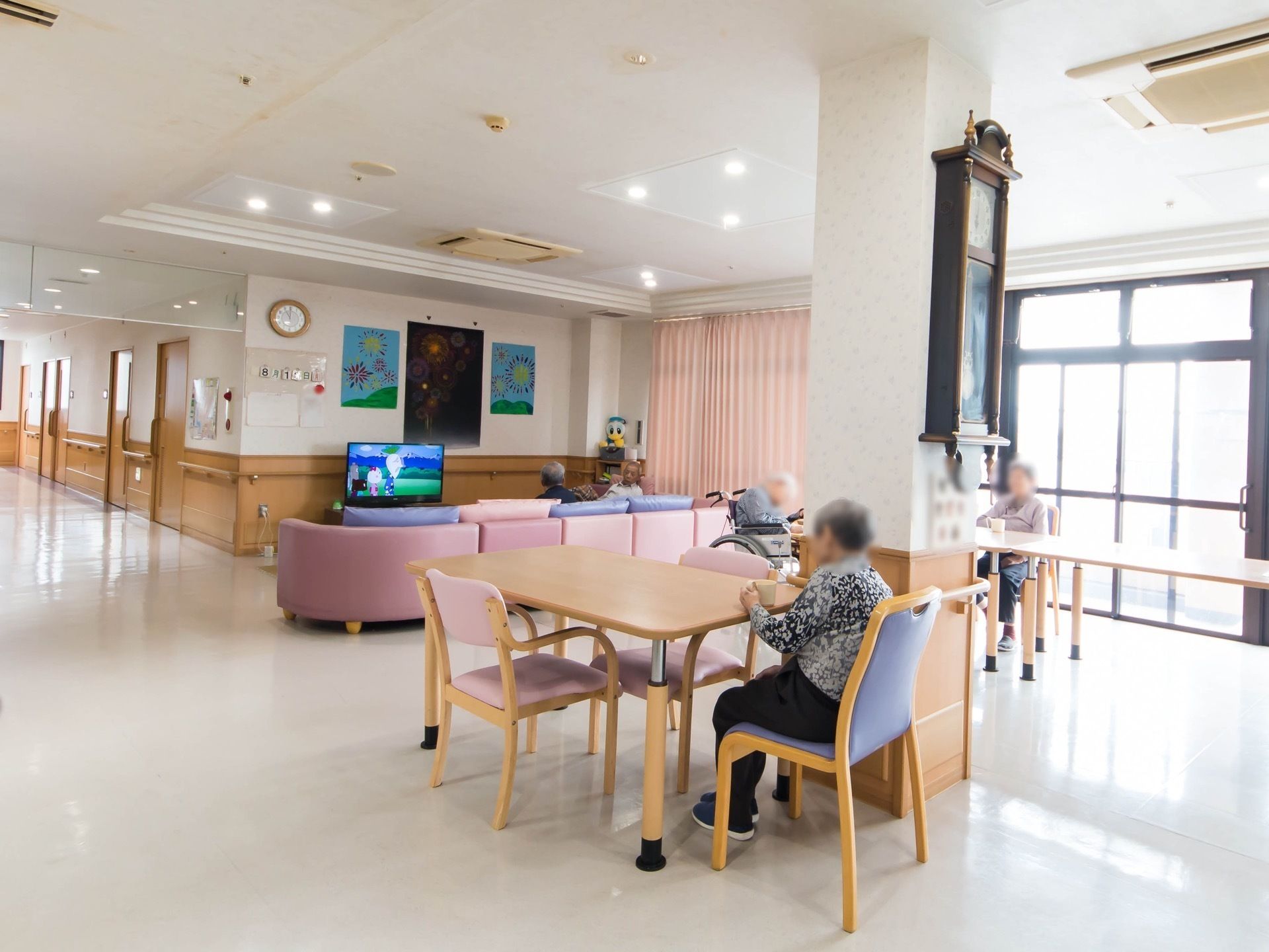 ダイニングテーブルと椅子、ソファがある部屋で自由に時間を過ごす入居者