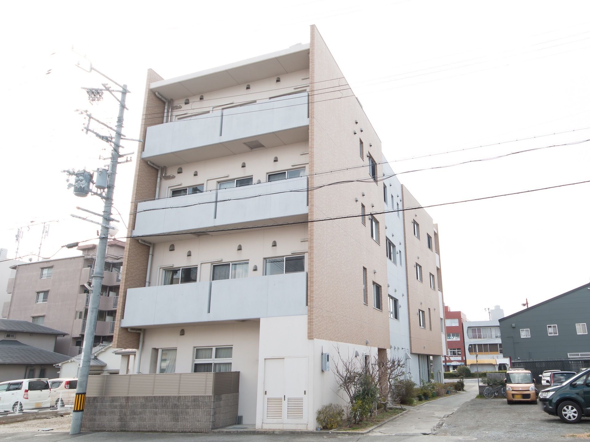 建物のすぐ隣に電柱が立っている。視界を遮る建物が周りにない。目の前に道路が走っている。大きなベランダが備わっている。