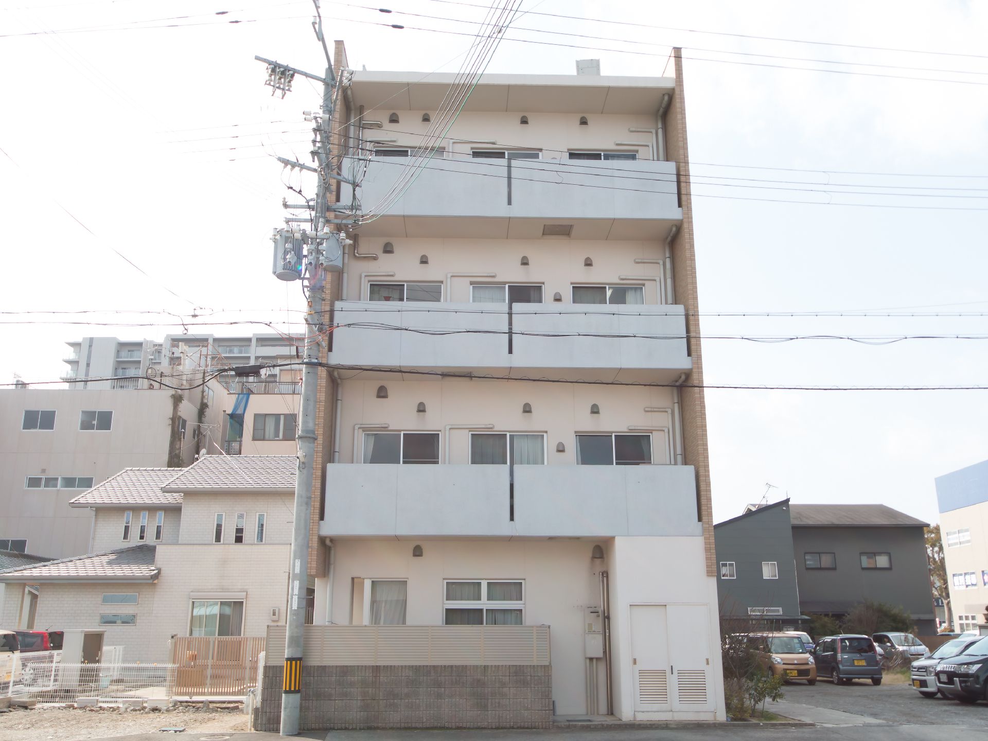 隣に駐車場がある、各部屋にベランダがある四階建ての建物