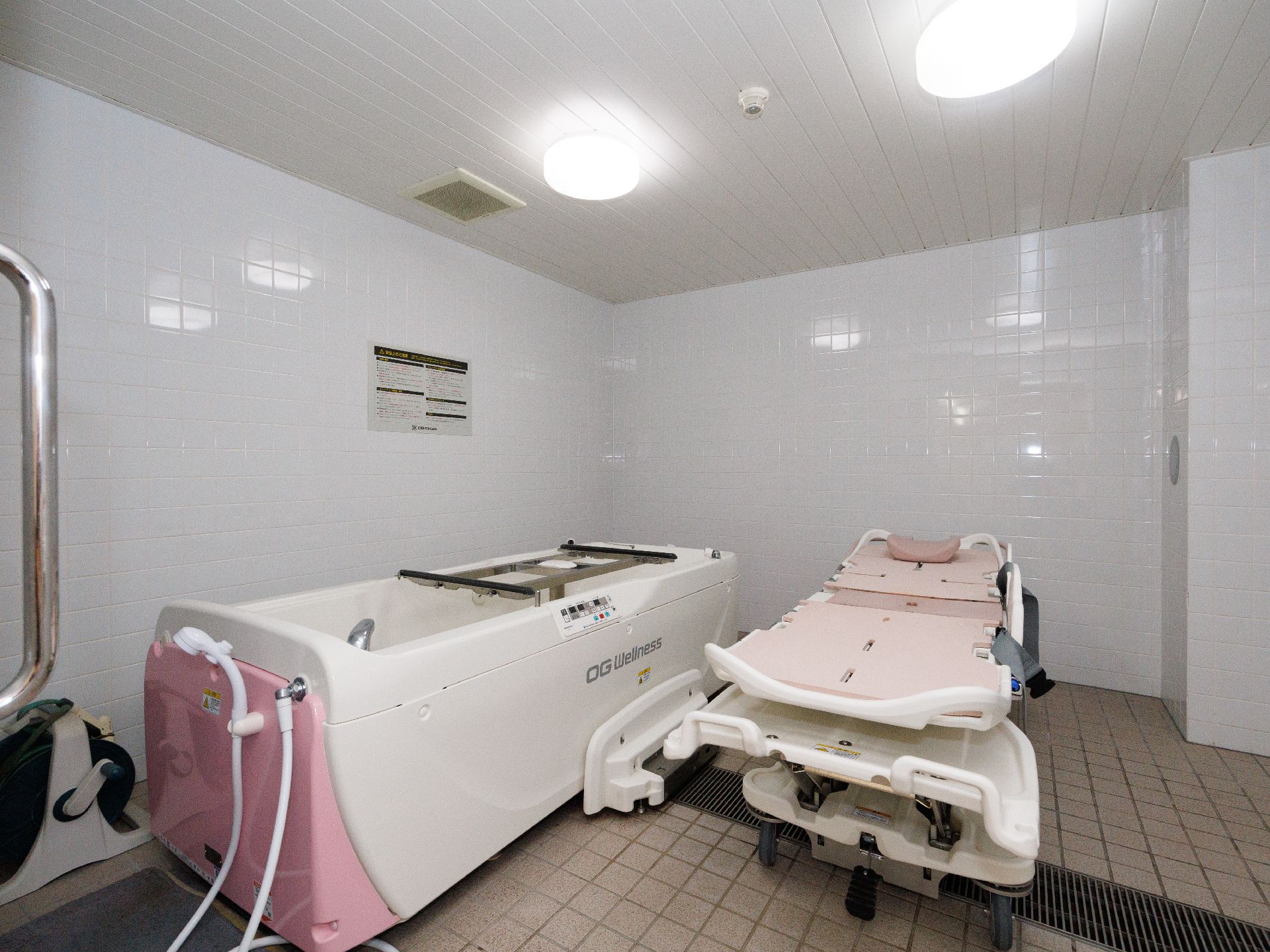 白い壁の部屋に置かれた機械浴用の浴槽とストレッチャー