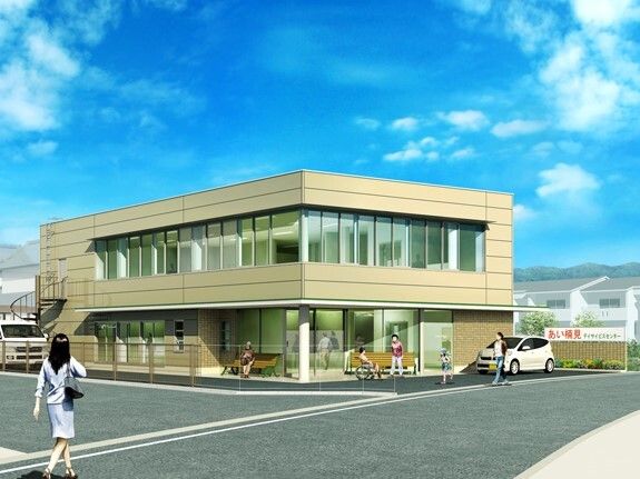 2階建てのベージュの建物の周りには背の高い建物がなく日当たりが良好。駐車スペースもあり、玄関の周りにはベンチもある。