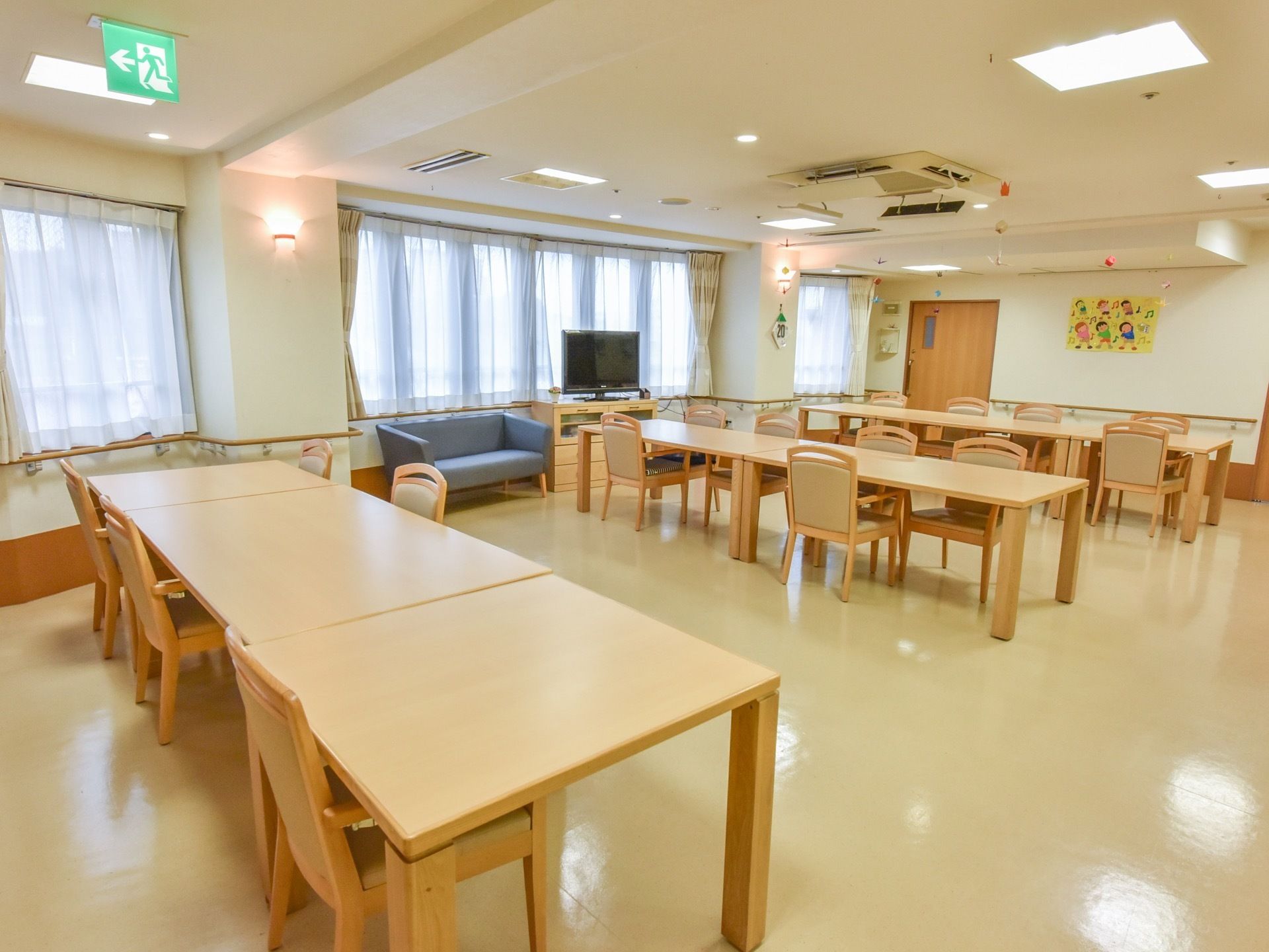 窓がたくさんあって明るいリビングダイニング。テレビも置かれ、テーブルと椅子の他にソファもあるので寛いで座れる。