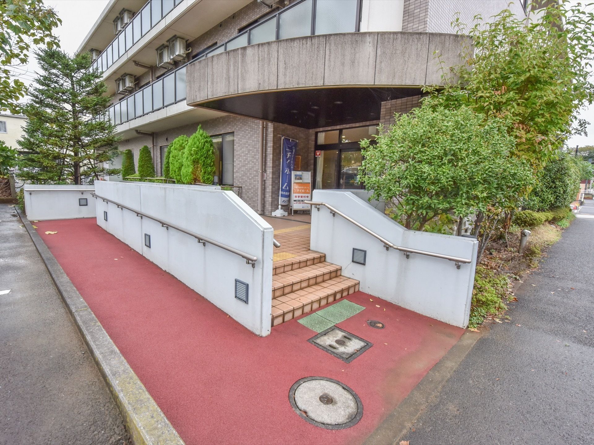 「ニチイホーム はるひ野」の外観。周辺に緑を配した、落ち着いたデザインの建物。