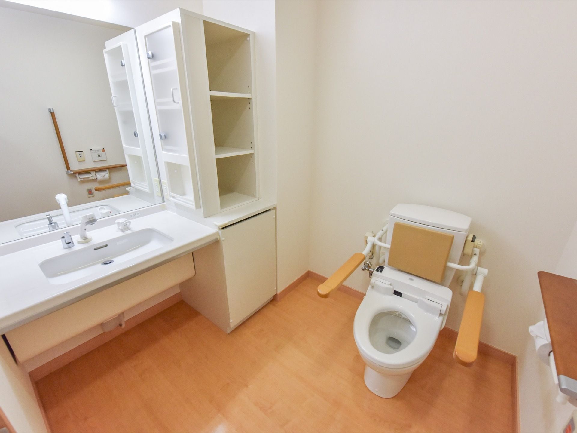 車いす対応型の洗面台に扉付きの収納、横にも3段収納がある。トイレも一緒でもとても広く、明るい空間になっている。
