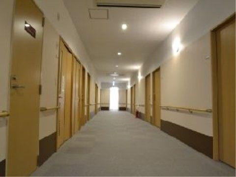 「スマイリングホーム メディス安中」の廊下。左右に介助手すりを設け、扉は引き戸になっている。